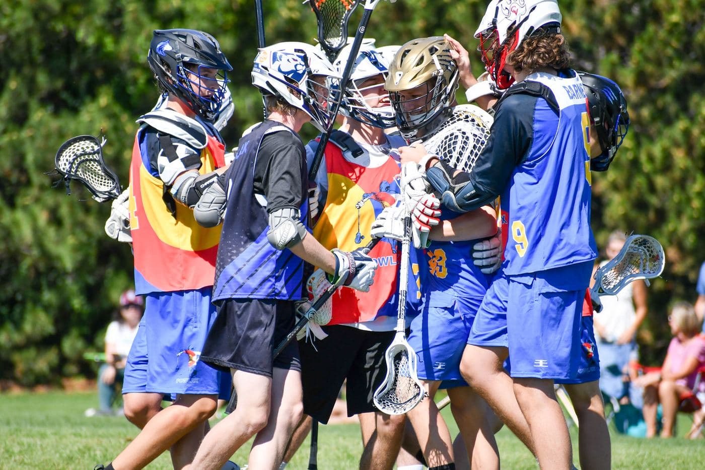 A coach and teammates congratulating a goalie on the field after a game